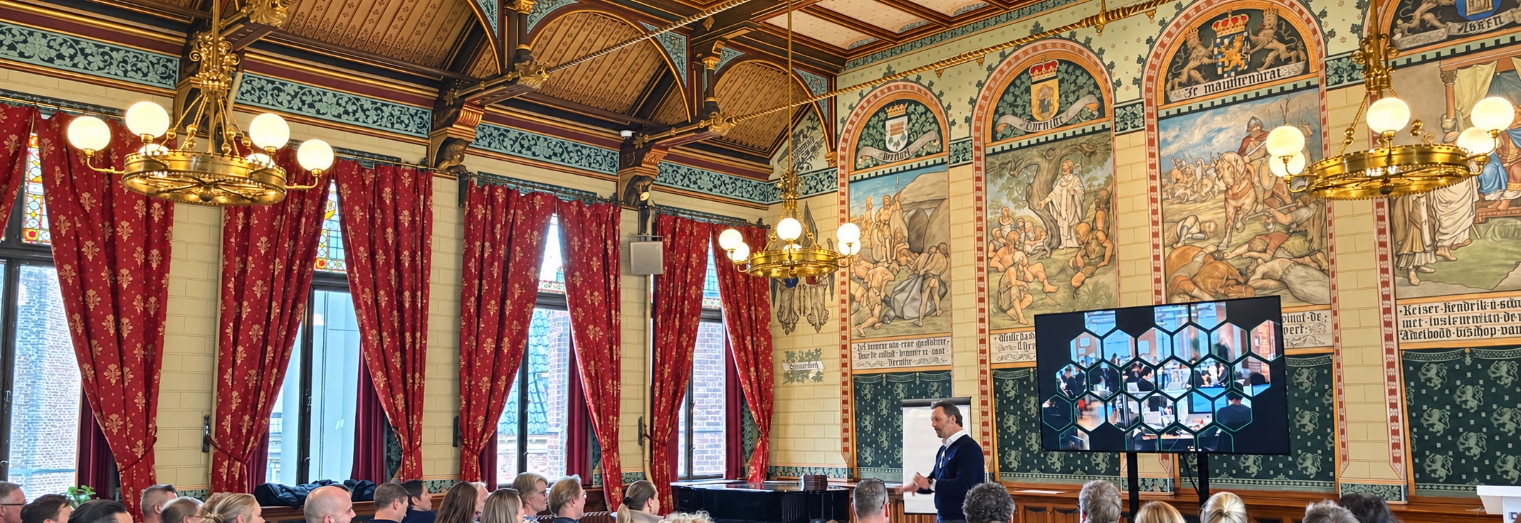 Bas van Kesteren spreekt voor publiek in een monumentale zaal